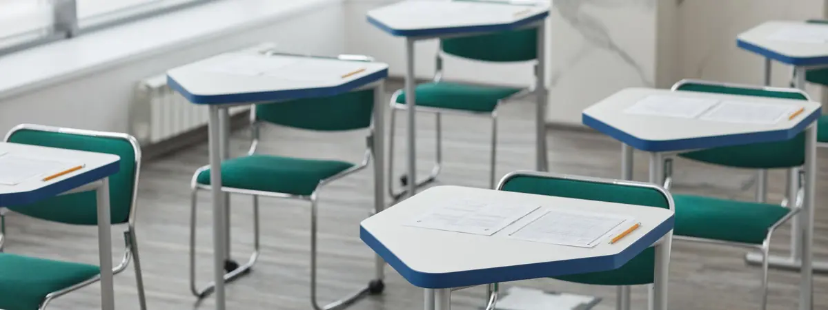 Empty classroom desks set with answer sheets and sharpened pencils, ready for an exam to begin